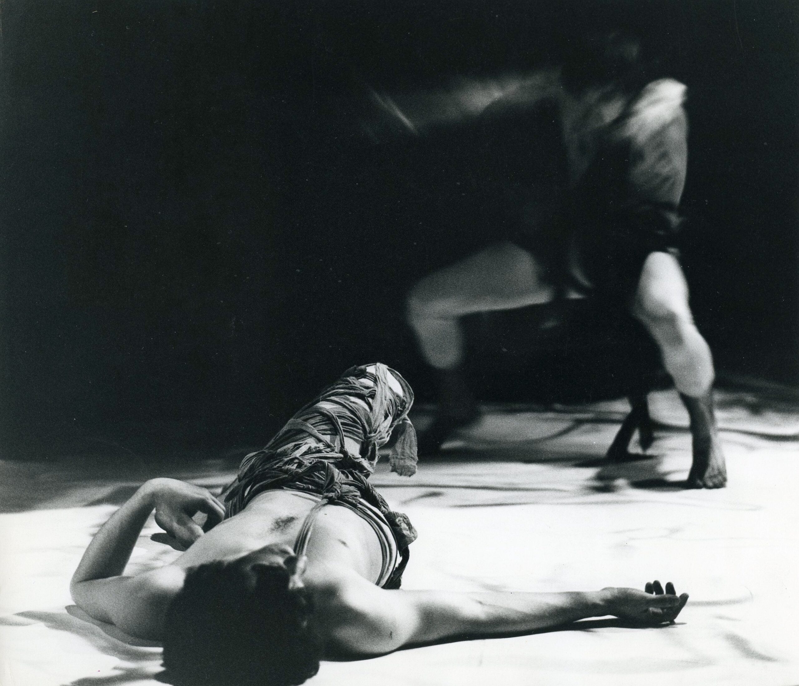 A black and white photo of a man laying on the floor.