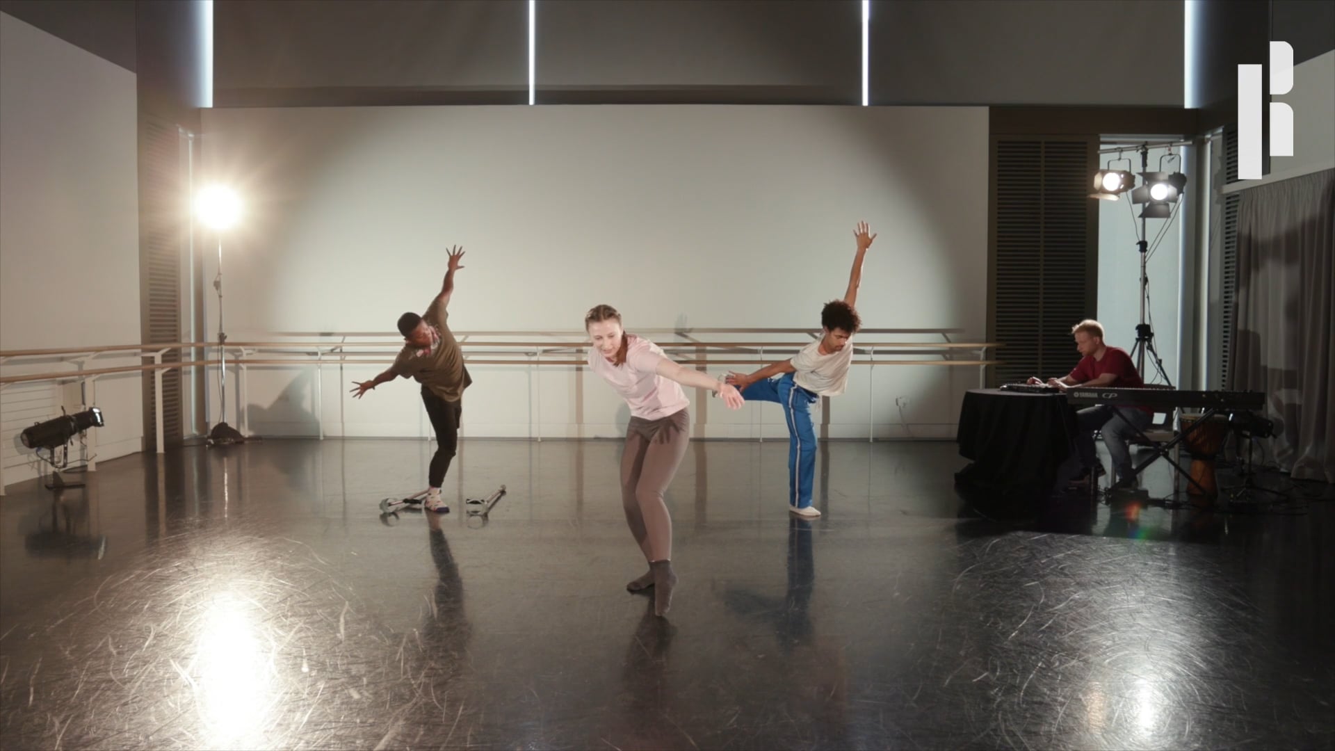A group of dancers are performing in a studio.