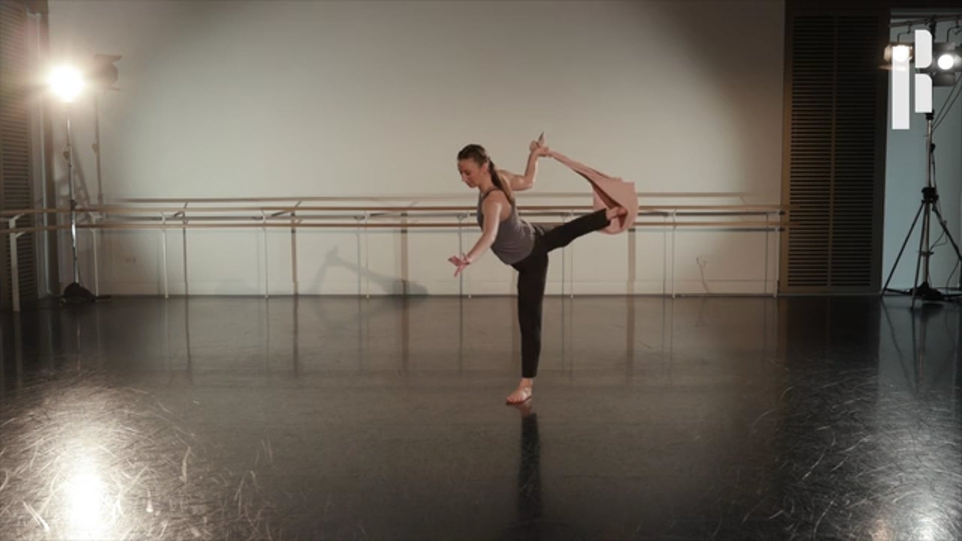 A young dancer is doing a pose in a dance studio.