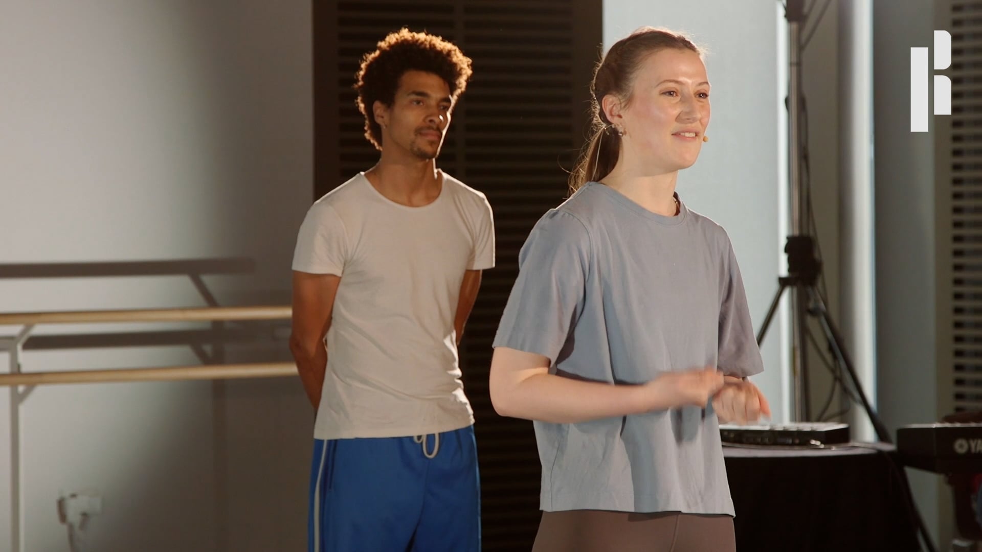 Two people standing next to each other in a dance studio.