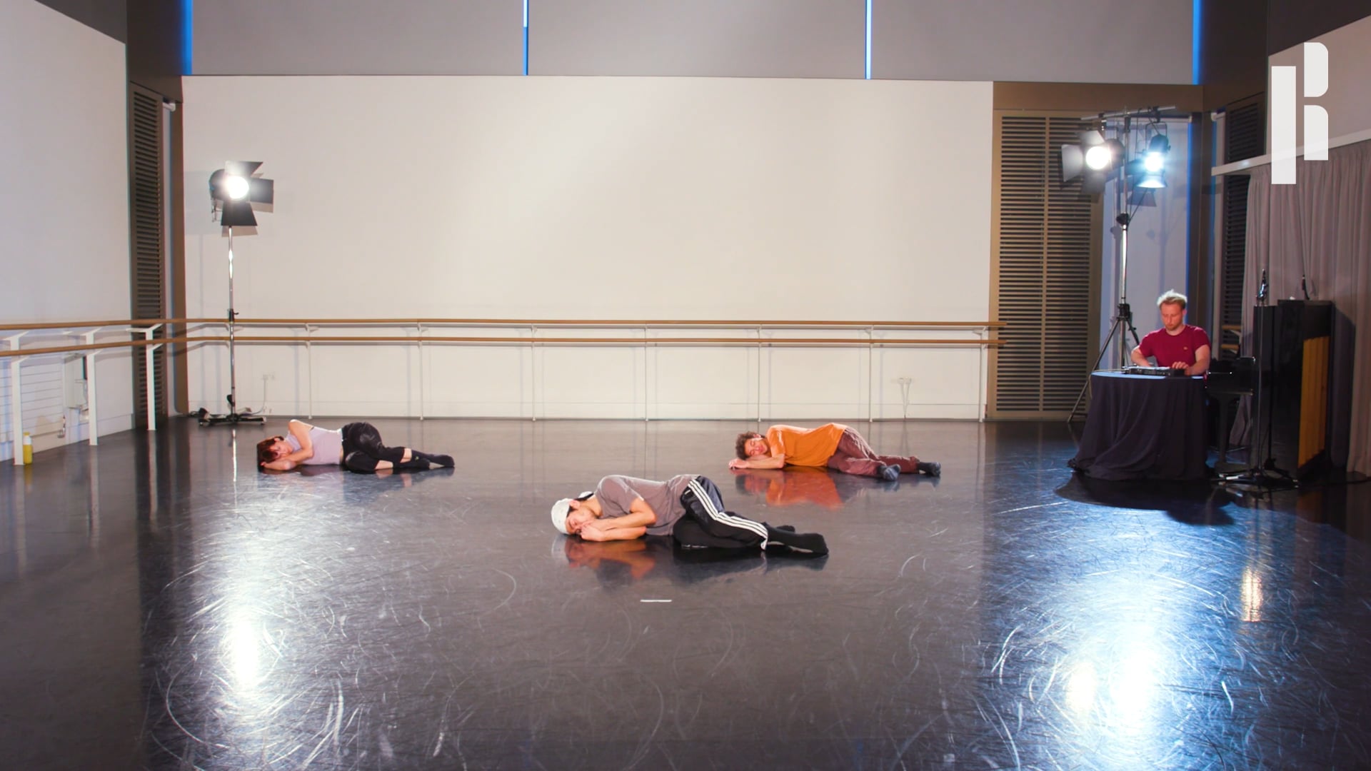 A group of people laying on the floor in a dance studio.