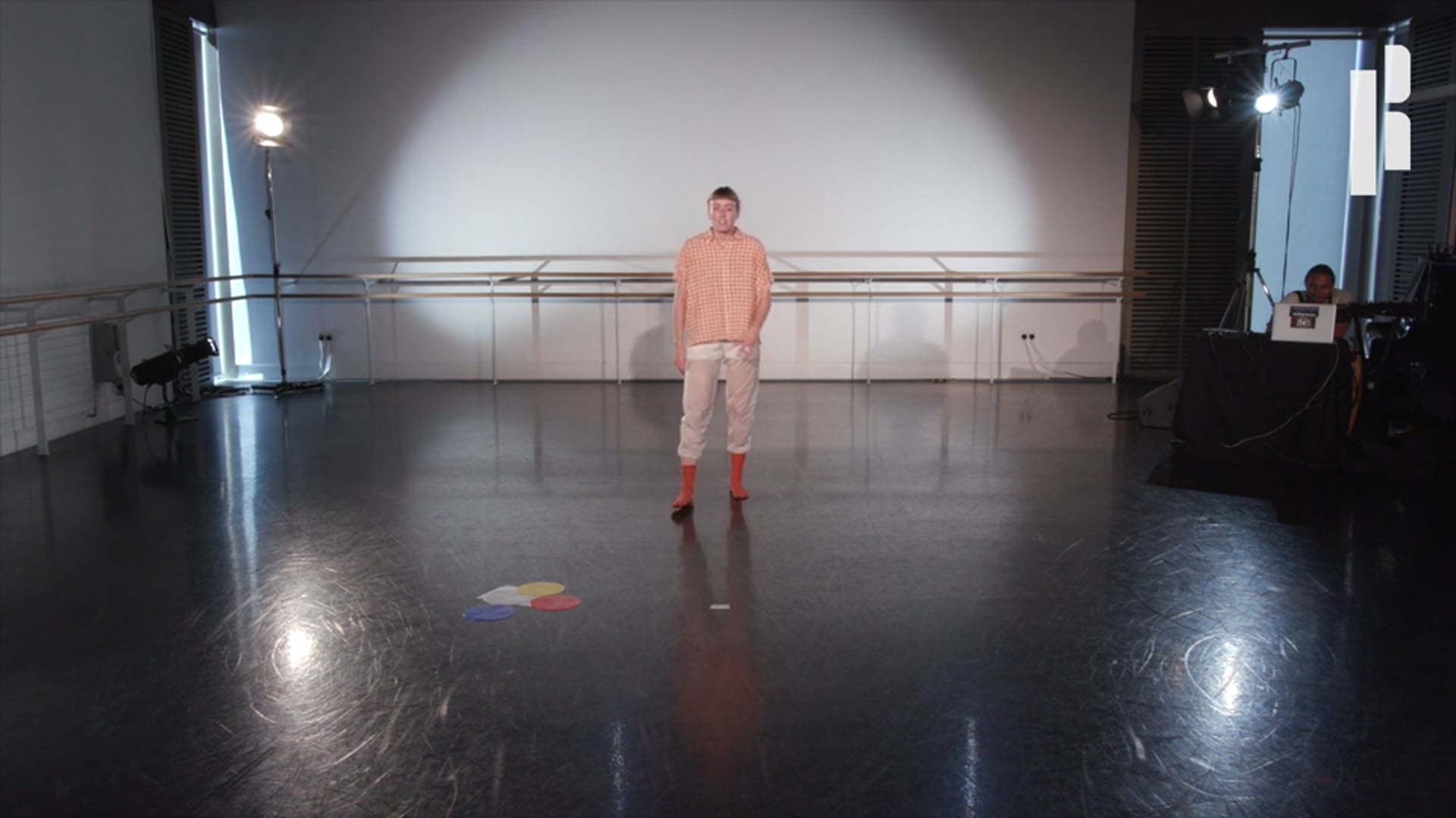 A woman is standing on a white floor in a dance studio.
