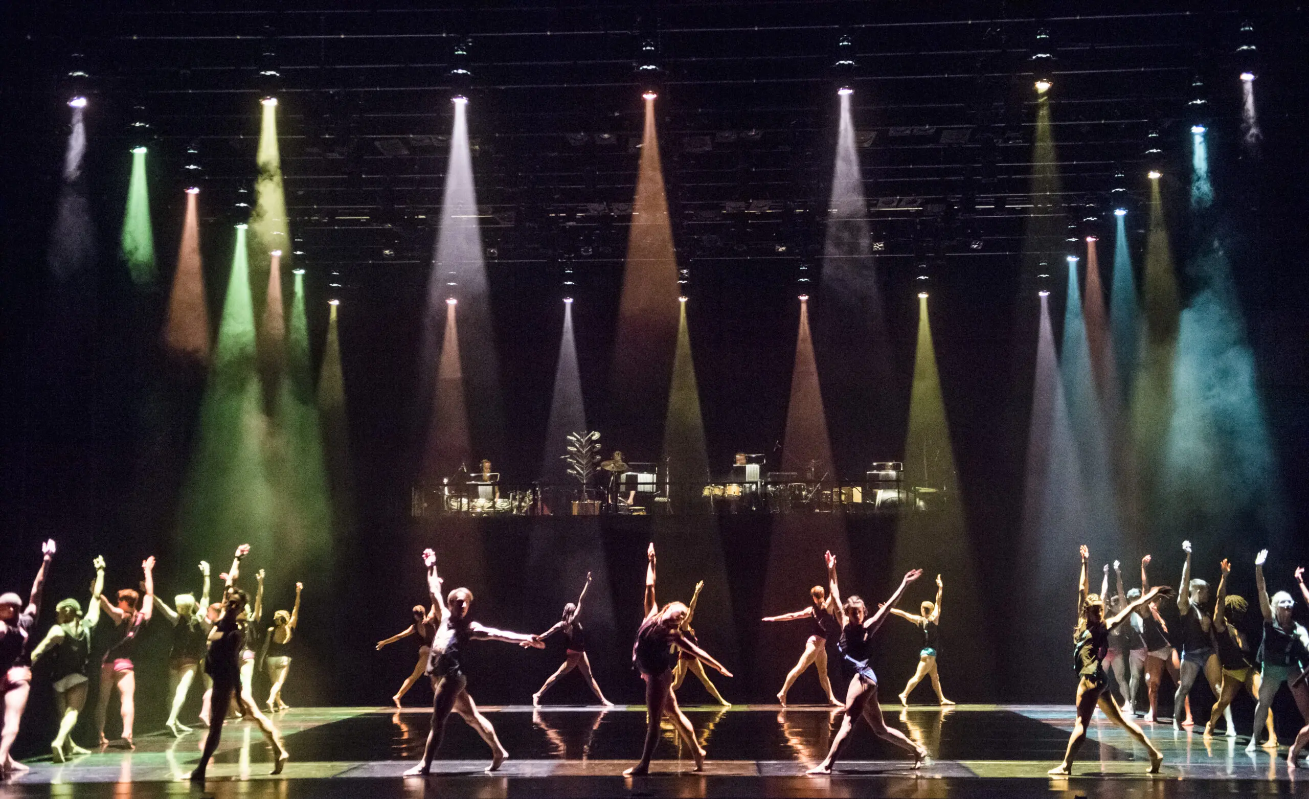 A group of dancers on stage with colorful lights.