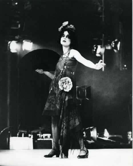 A black and white photo of a woman in a dress holding a fan.