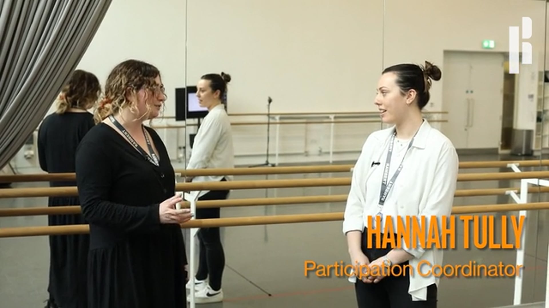 Two women in a dance studio talking to each other.