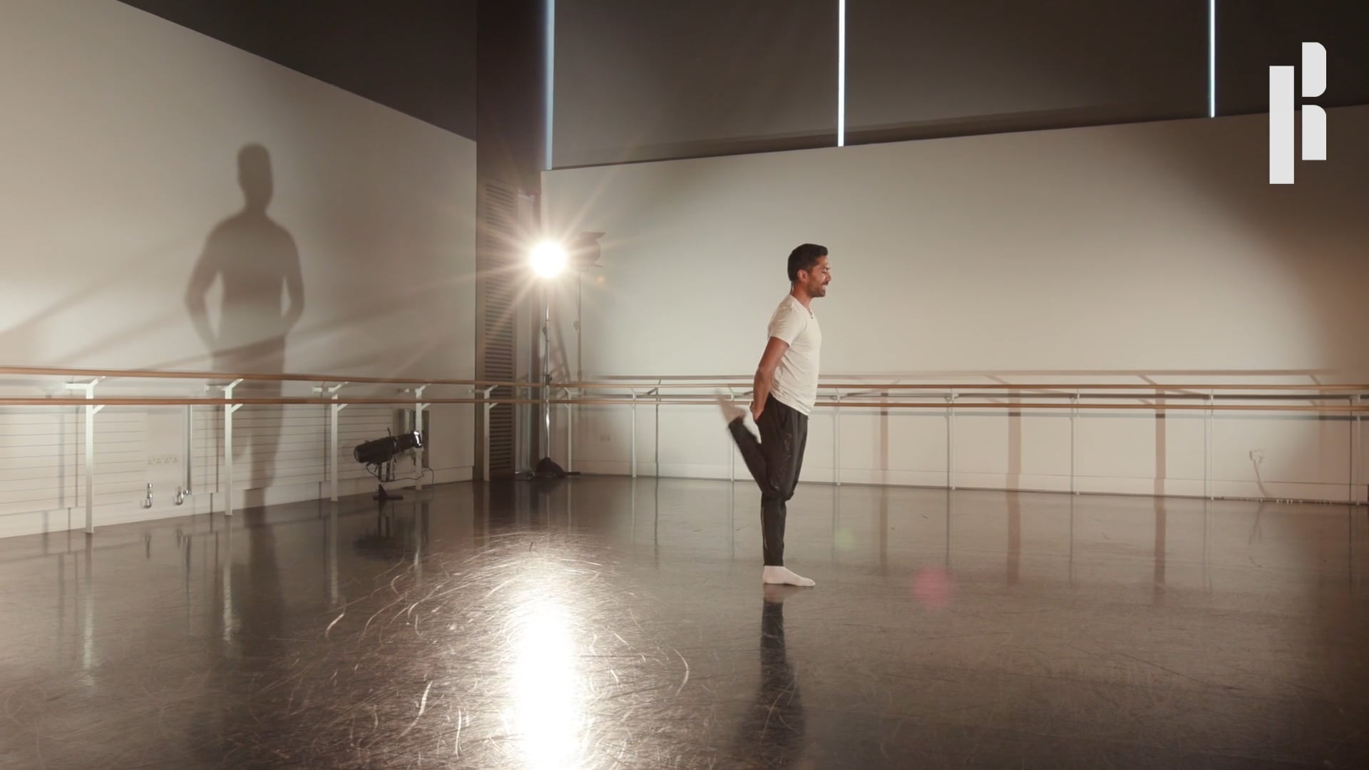 A man is standing in a dance studio with a shadow.
