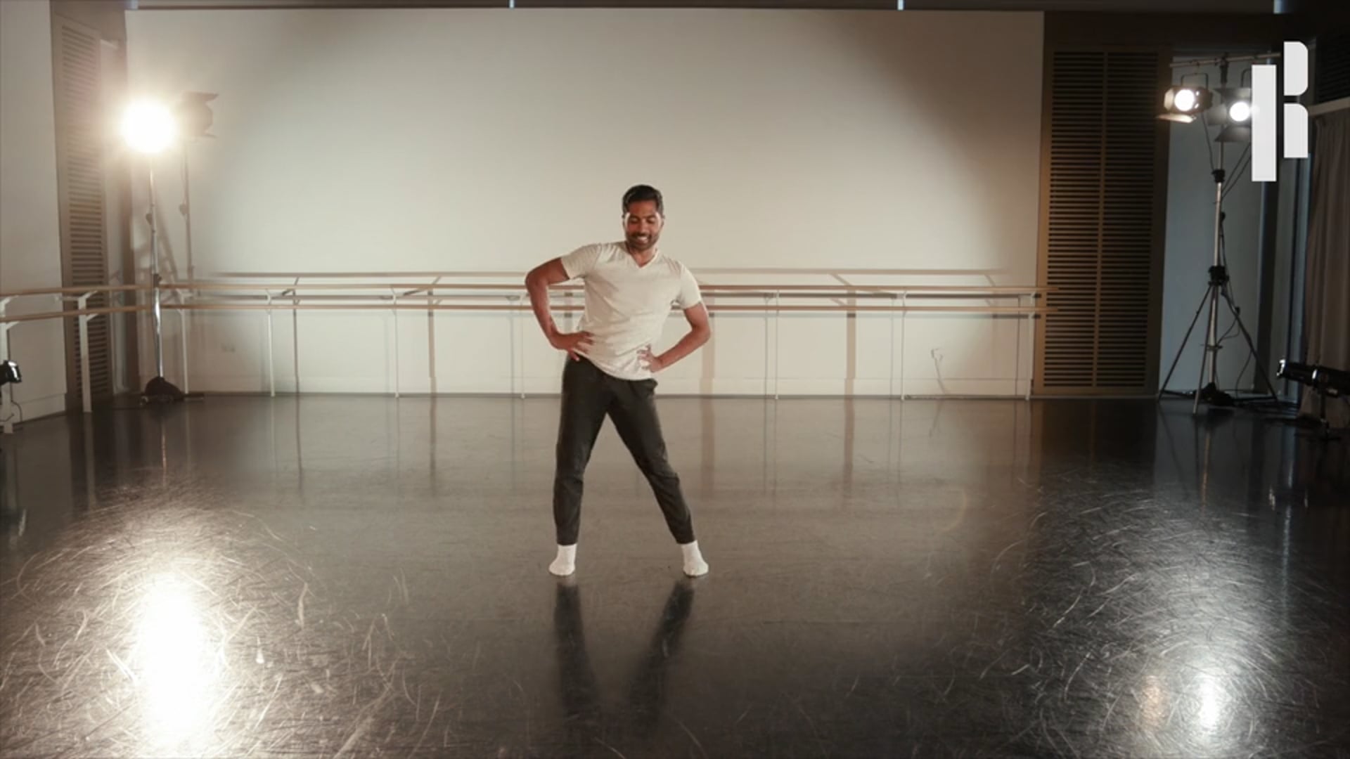 A man in a white shirt is standing in a dance studio.
