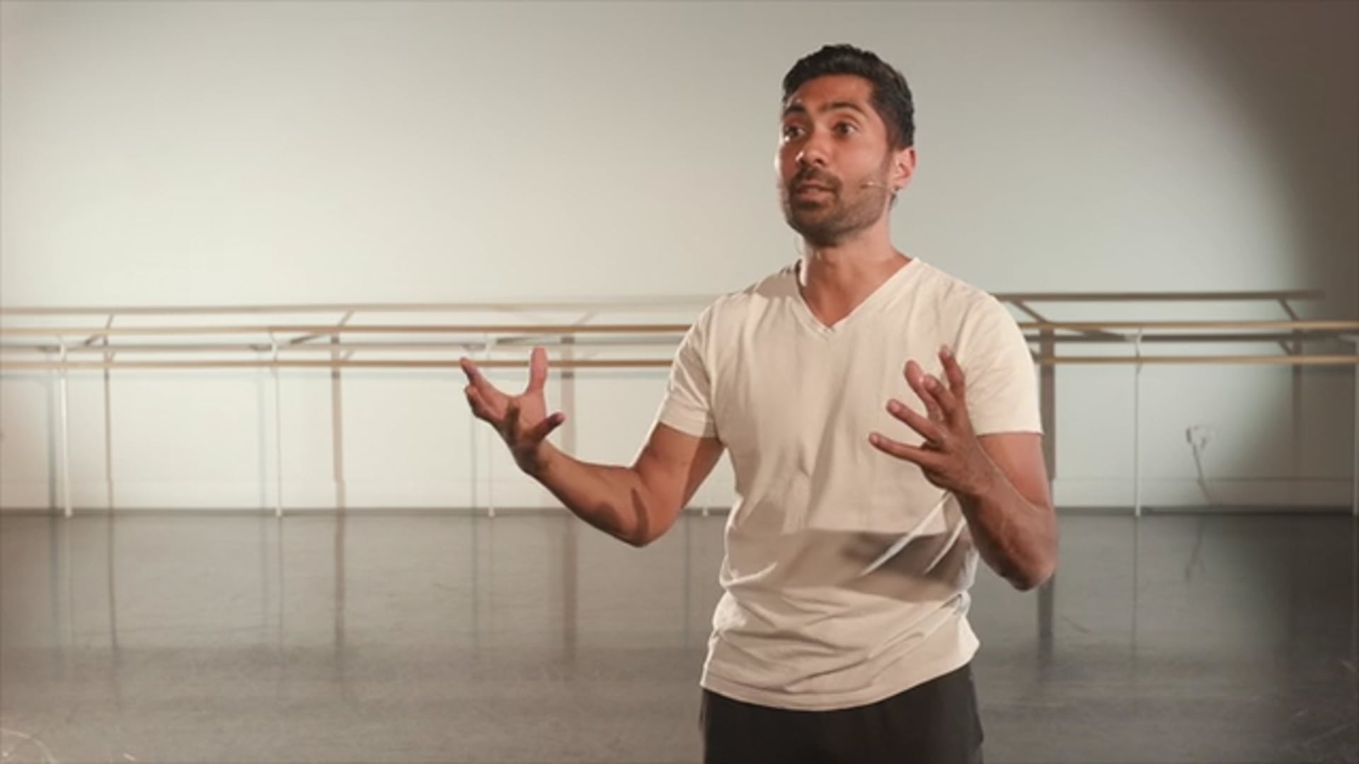 A man in a white shirt standing in a dance studio.