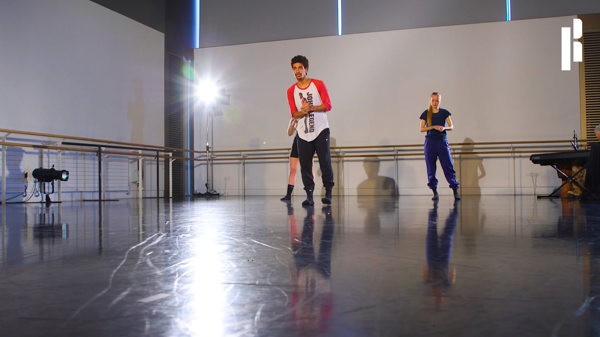 Two people standing in a dance studio.
