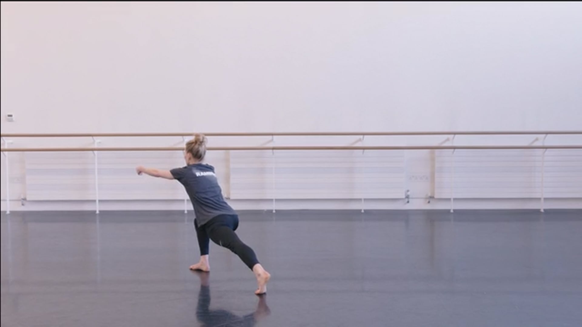 A woman practicing ballet in a dance studio.