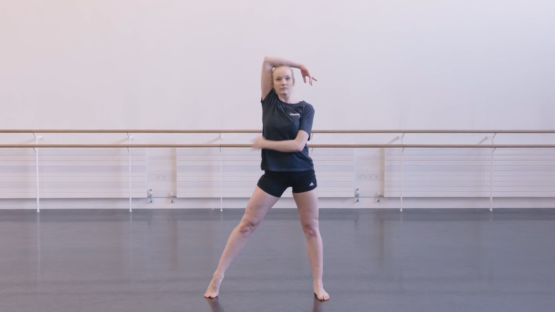 A young dancer is standing in a dance studio.