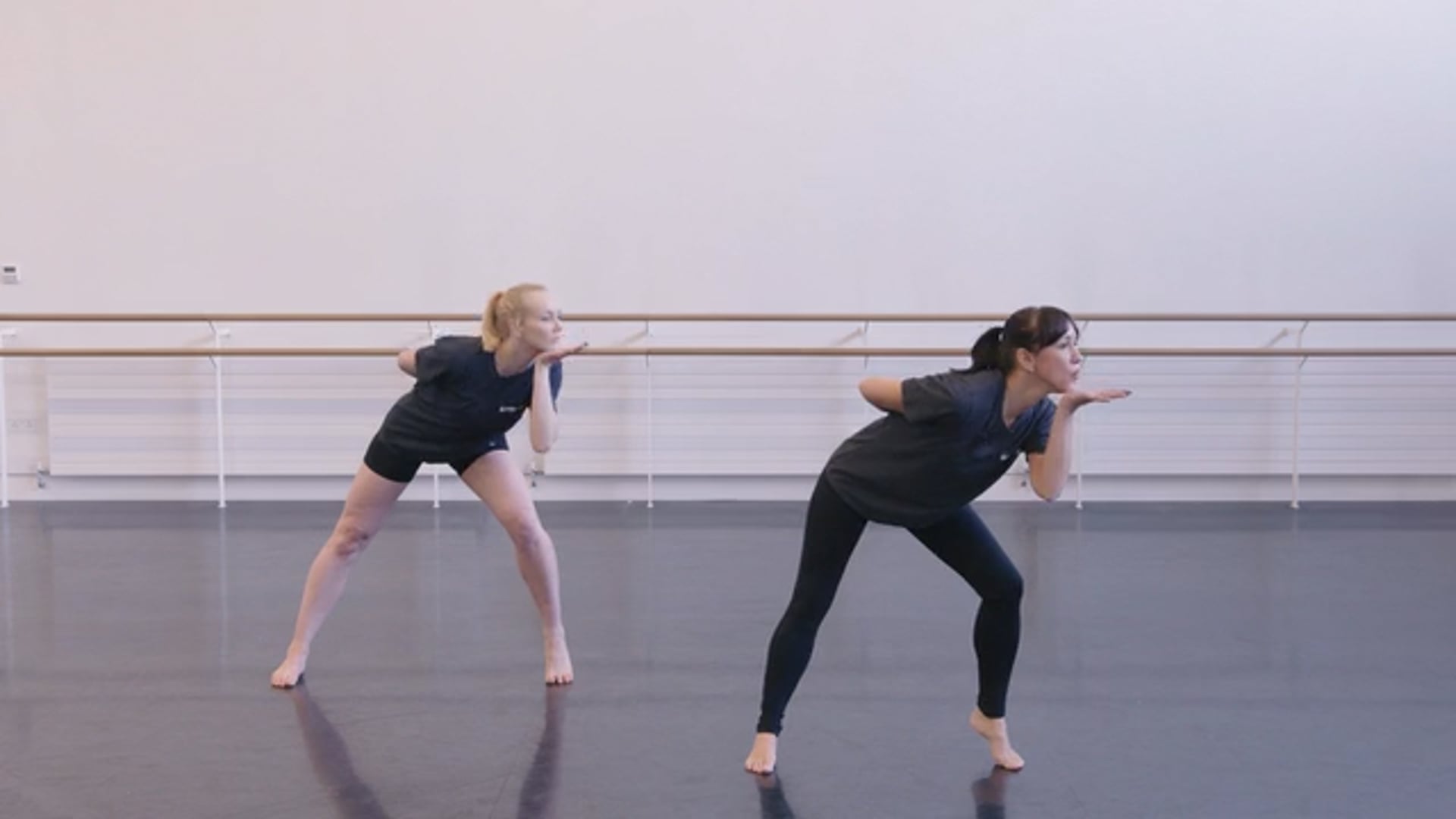 Two dancers are standing in a dance studio.