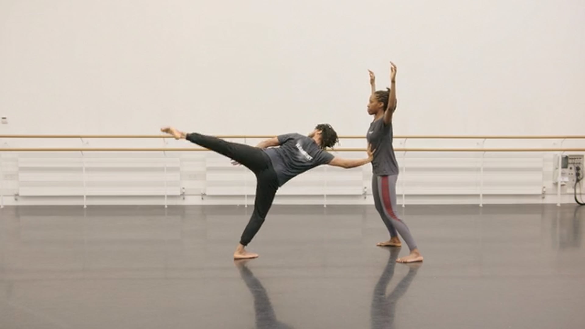Two dancers practicing in a dance studio.