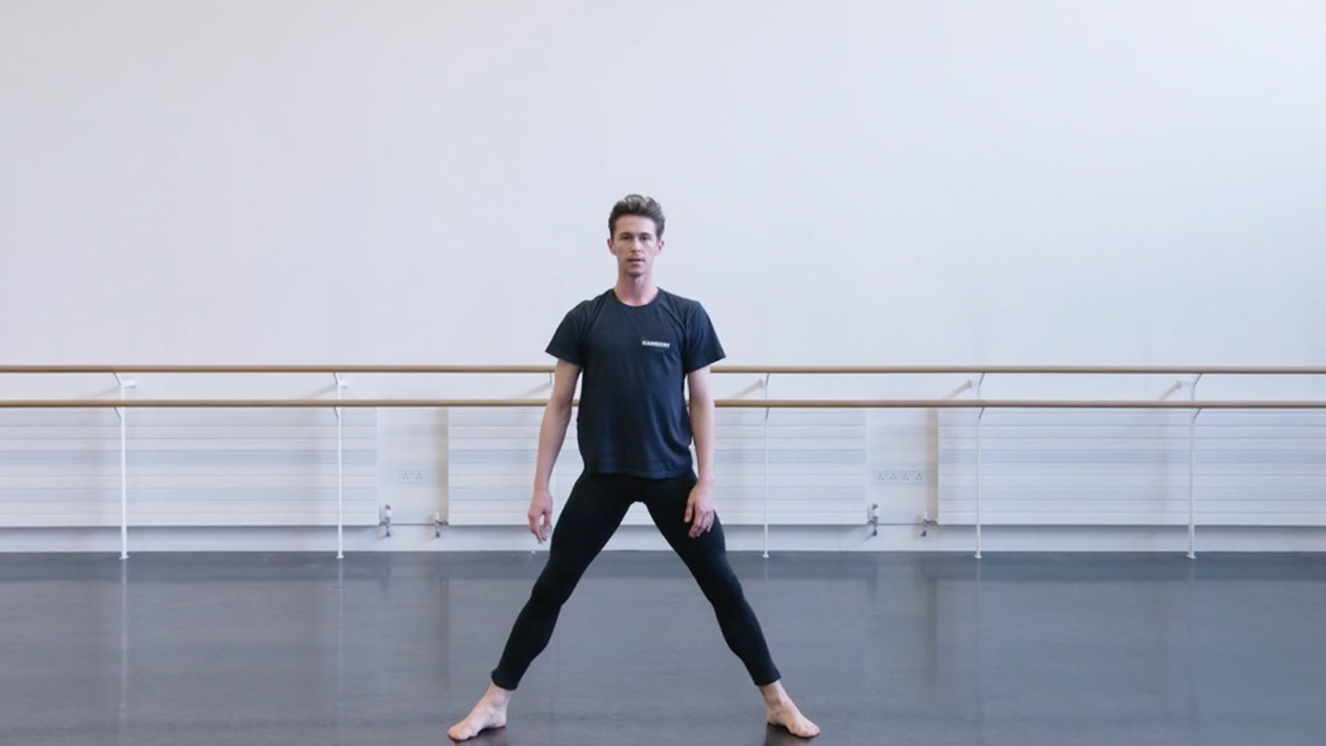 A man in a black shirt is standing in a dance studio.