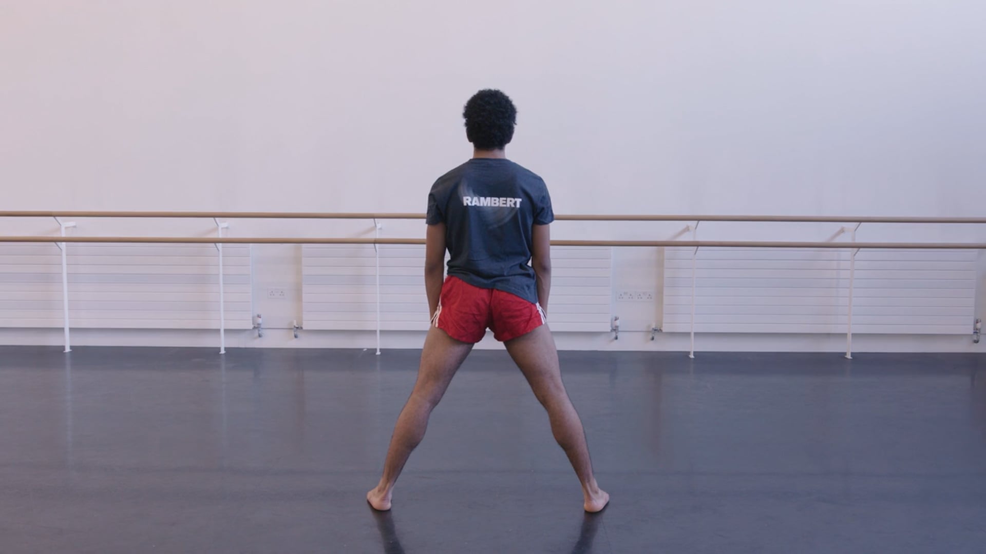 A man in shorts standing in a dance studio.