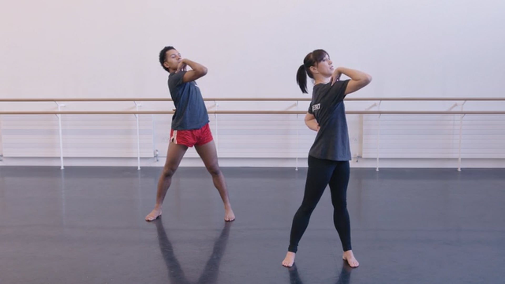 Two dancers standing in a dance studio.