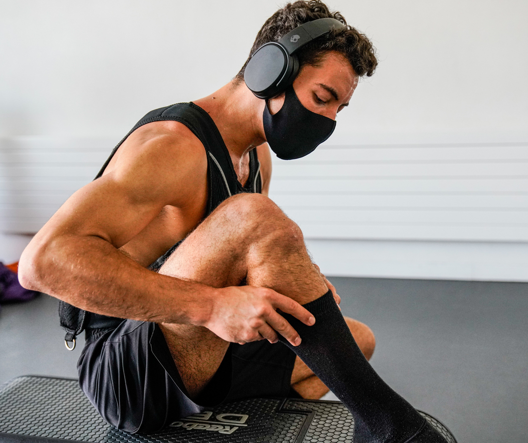 a man wearing a mask and knee pads sitting on a mat.