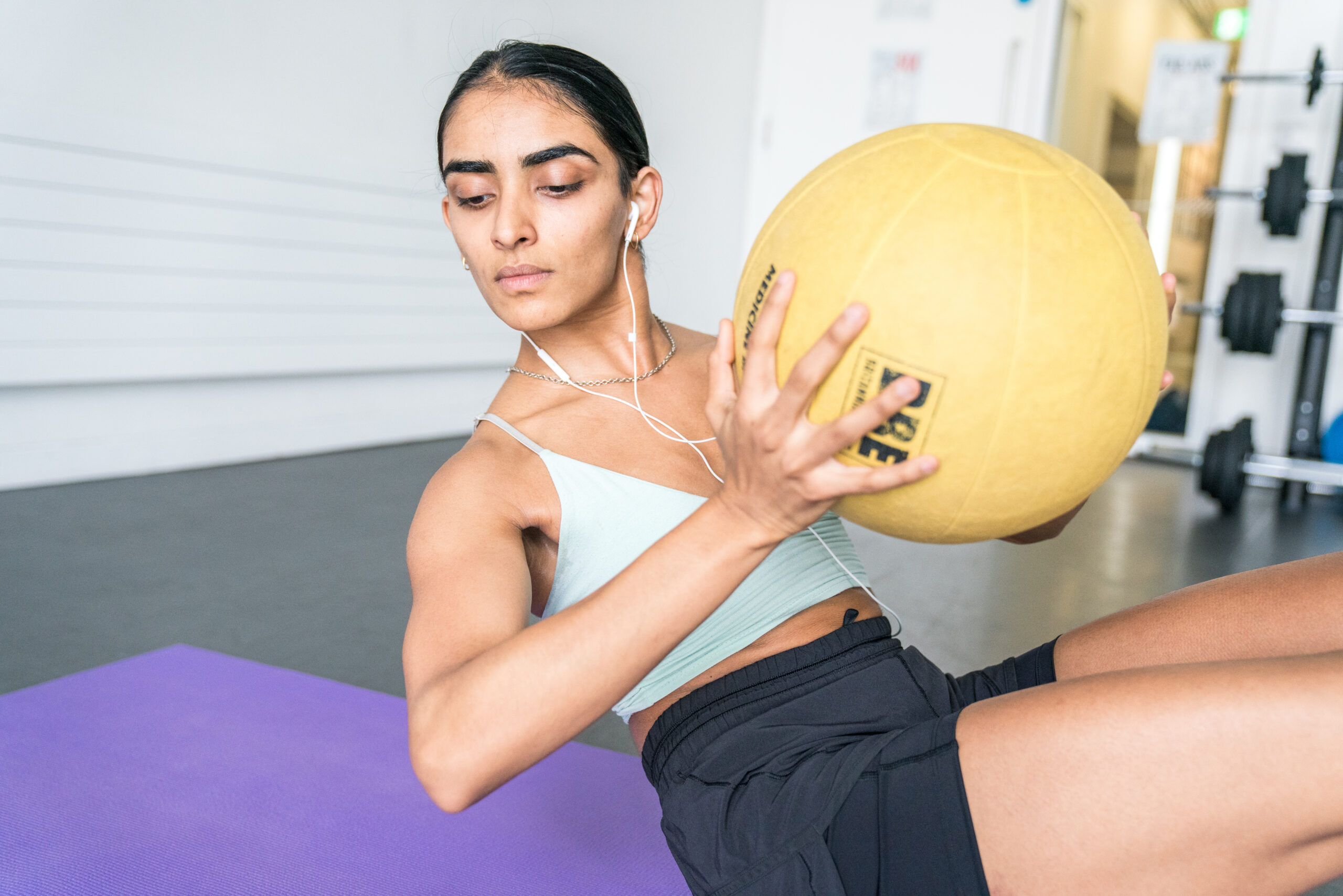 a woman holding a yellow ball in a gym.
