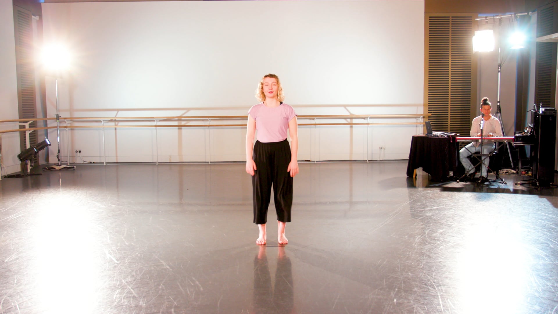 a woman standing on a stage in a dance studio.
