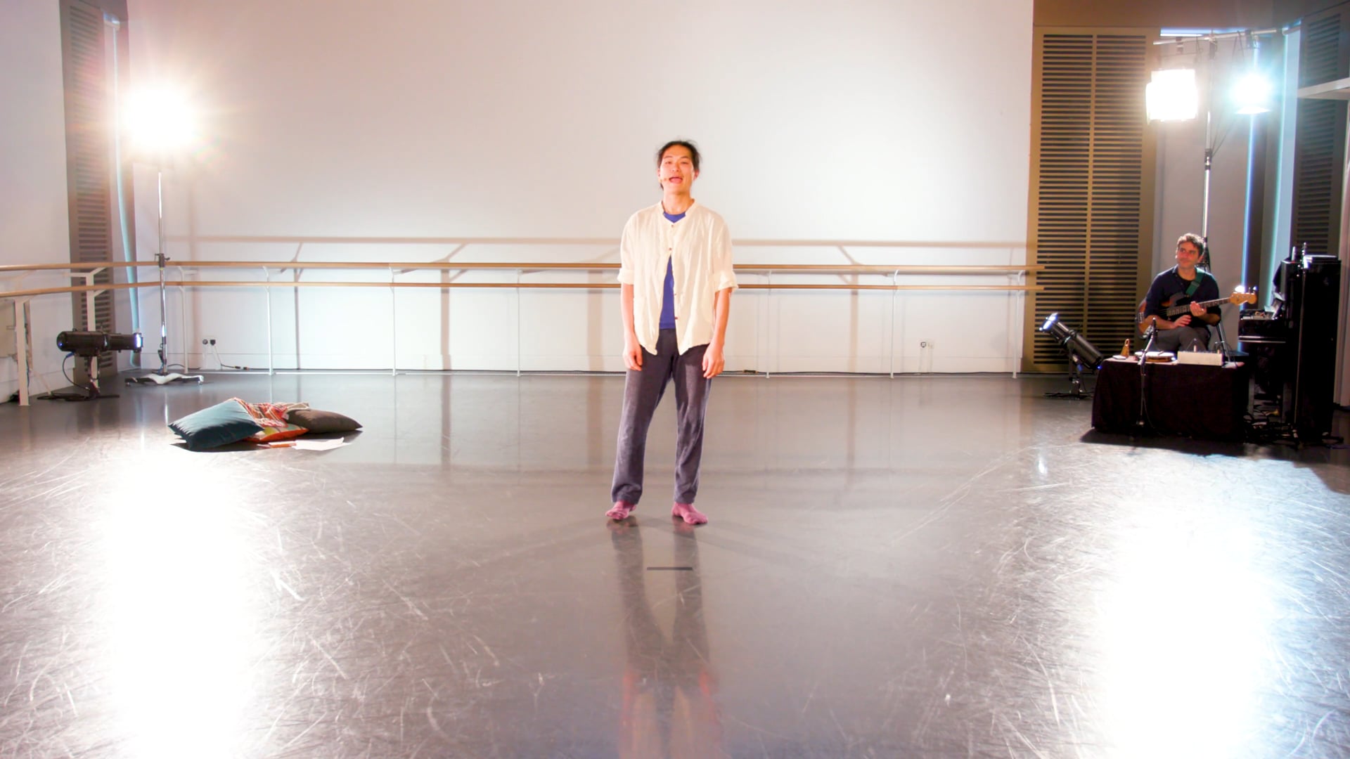 a woman standing on a stage with a man laying on the floor.