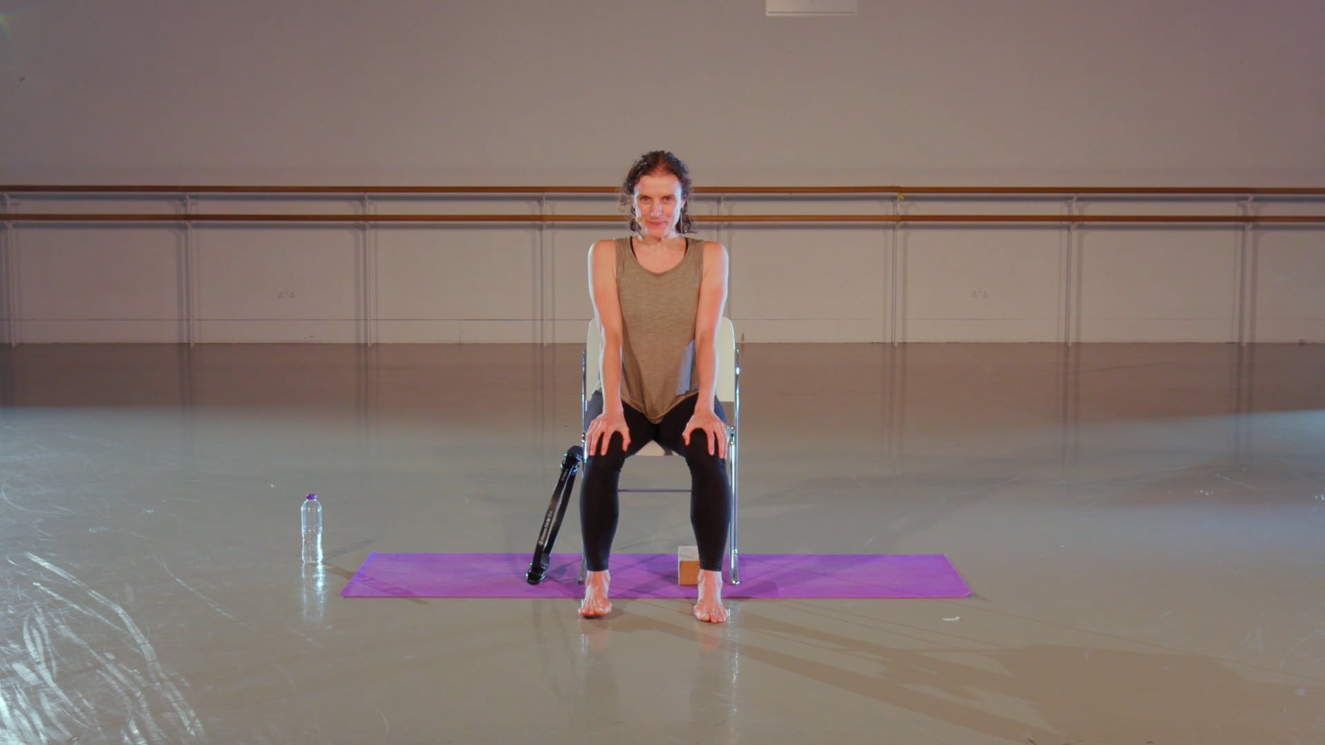 a woman sitting on a yoga mat with her legs crossed.