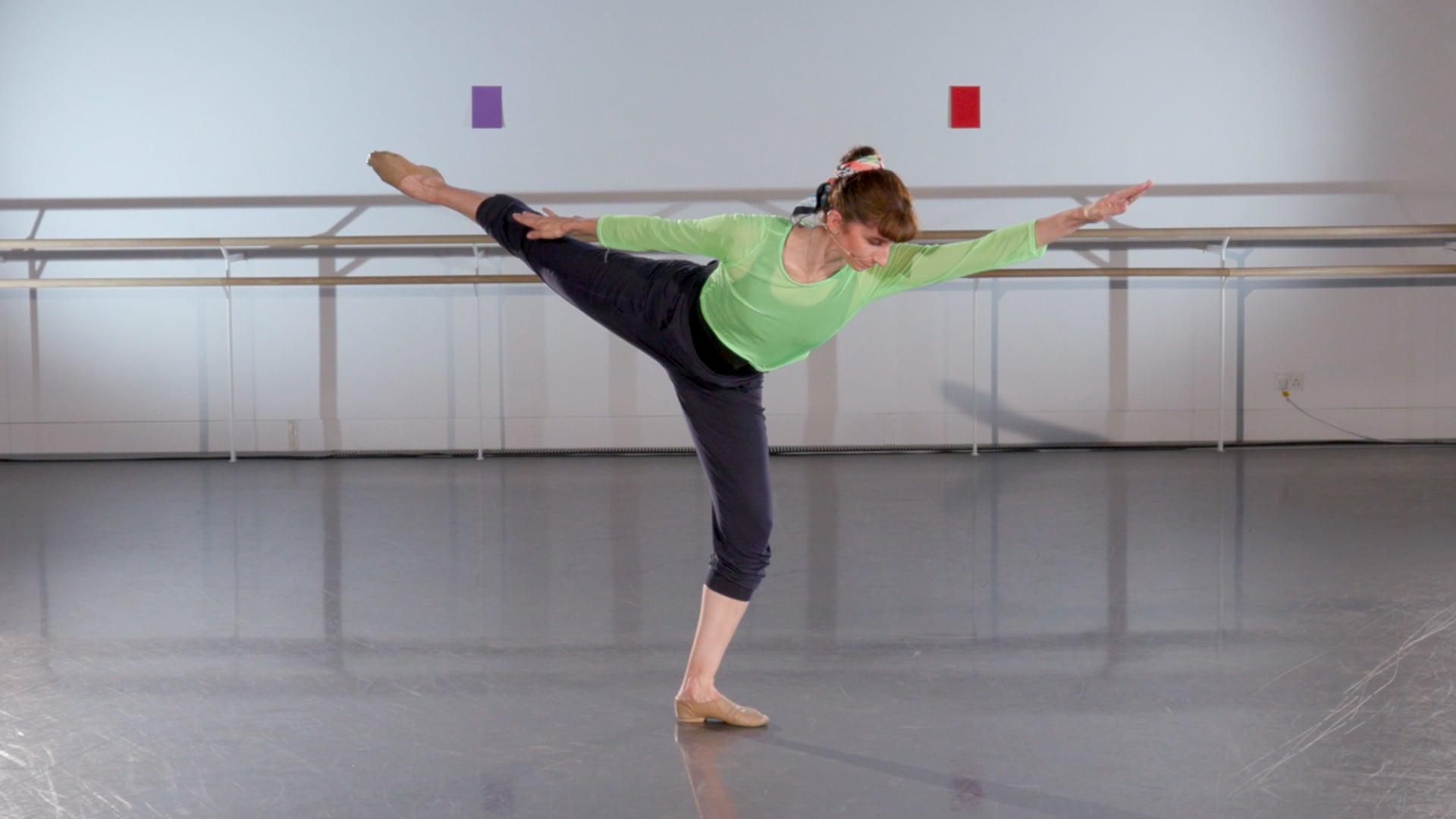 a woman in a green shirt is doing a ballet move.