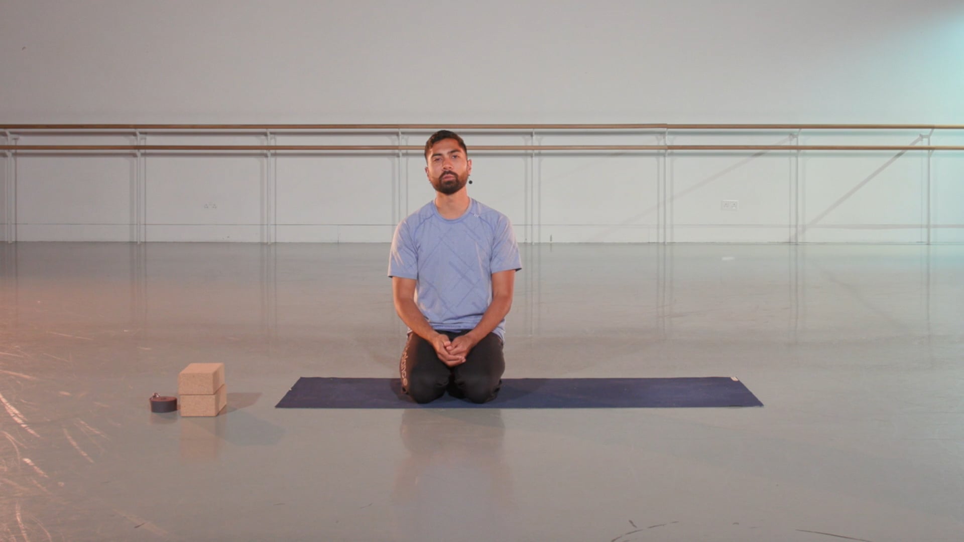 a man sitting on a yoga mat in a large room.