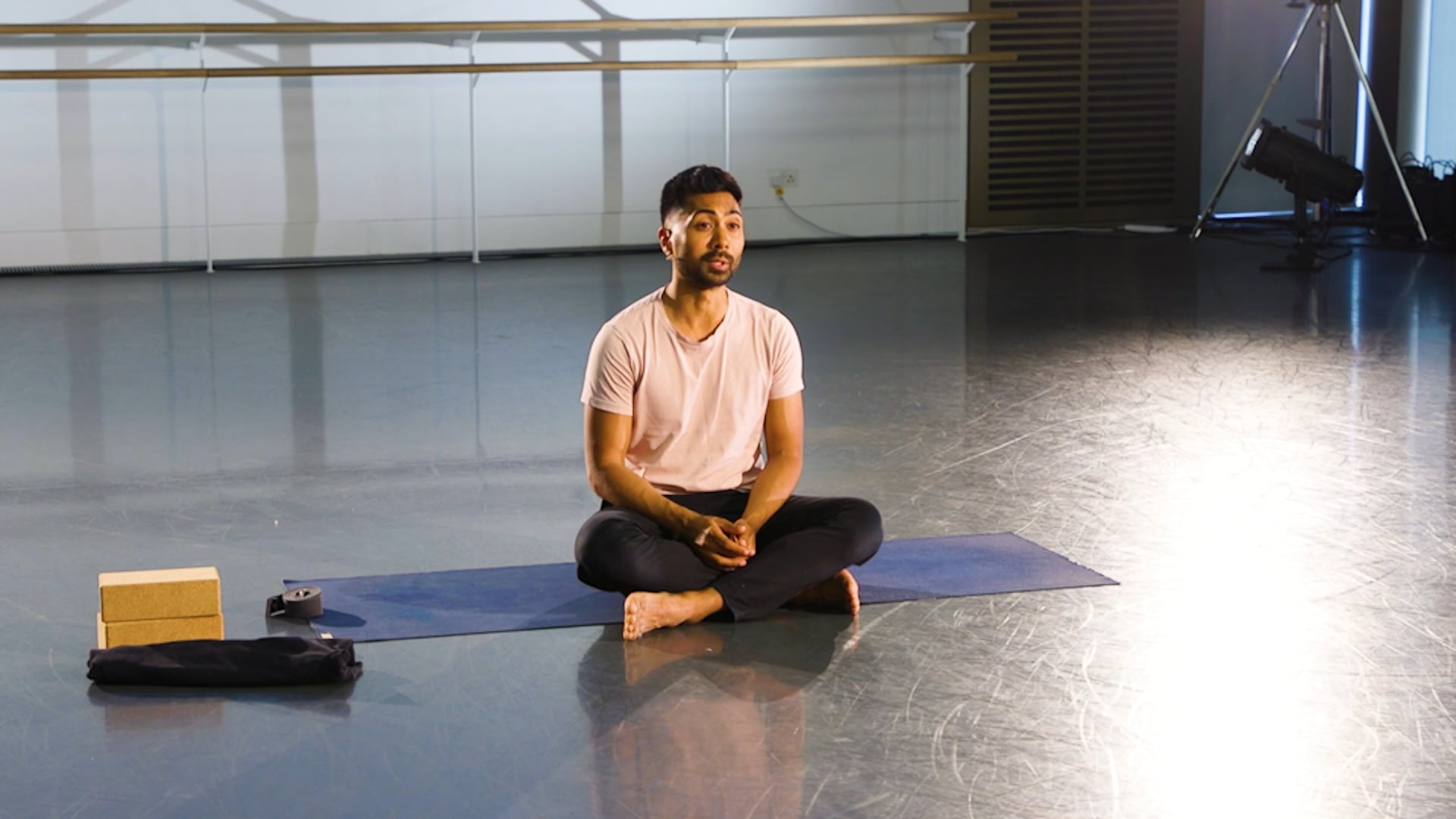 a man sitting on a yoga mat in a gym.