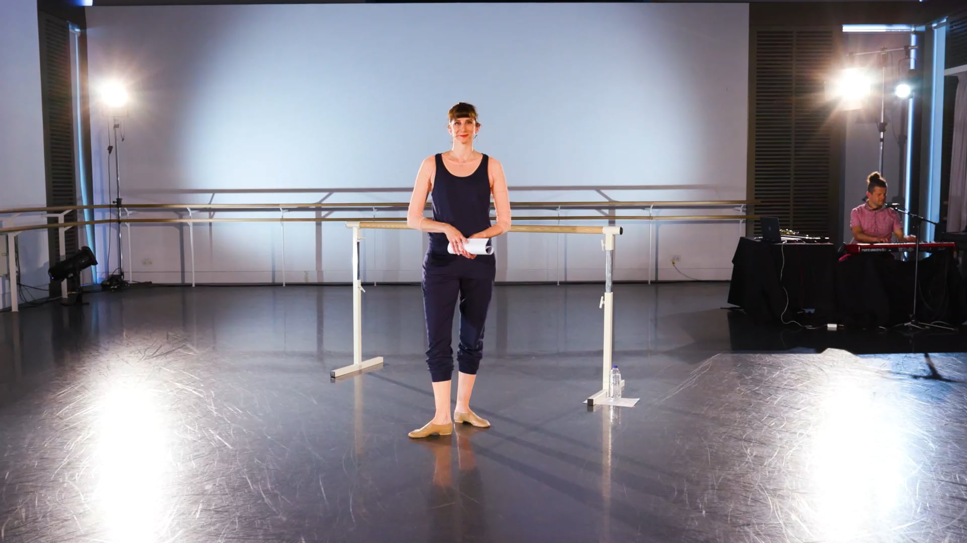 a woman standing in front of a rail in a dance studio.