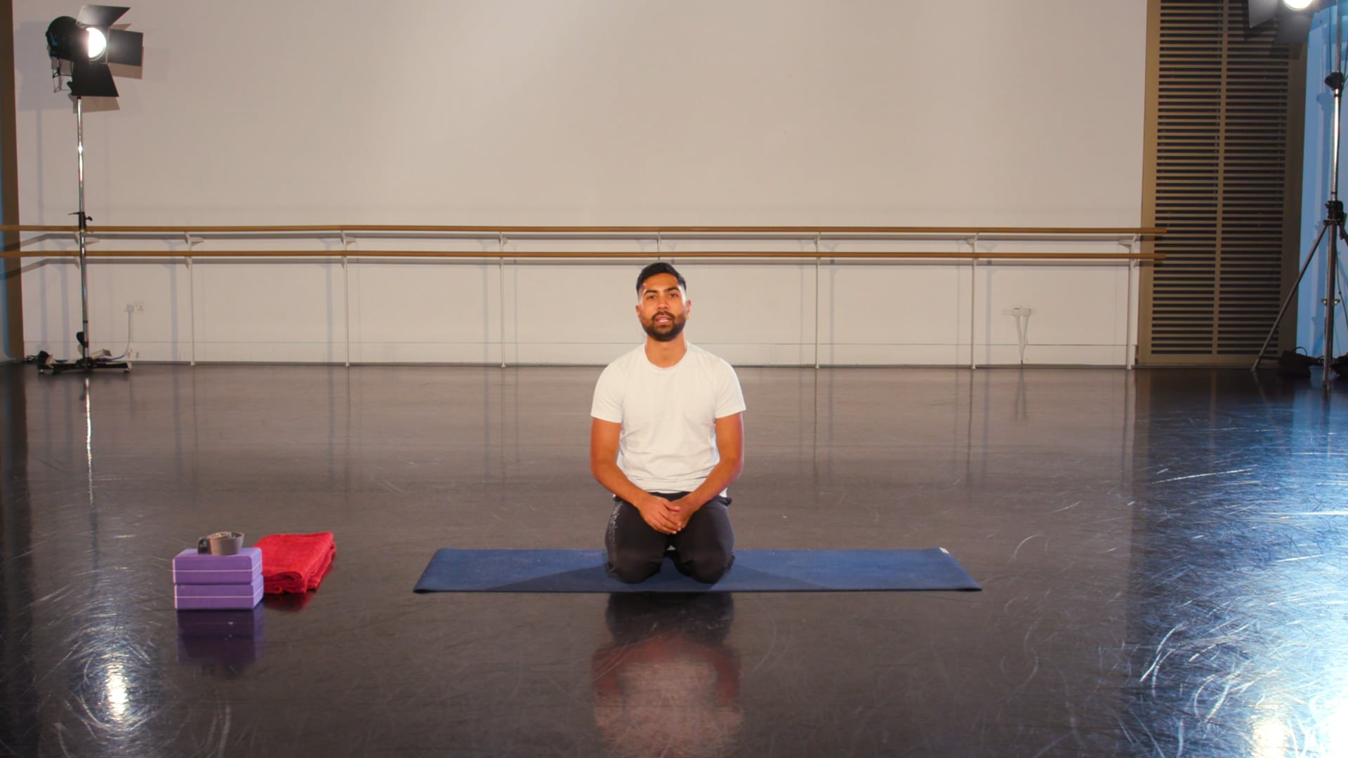 a man sitting on a yoga mat in a room.