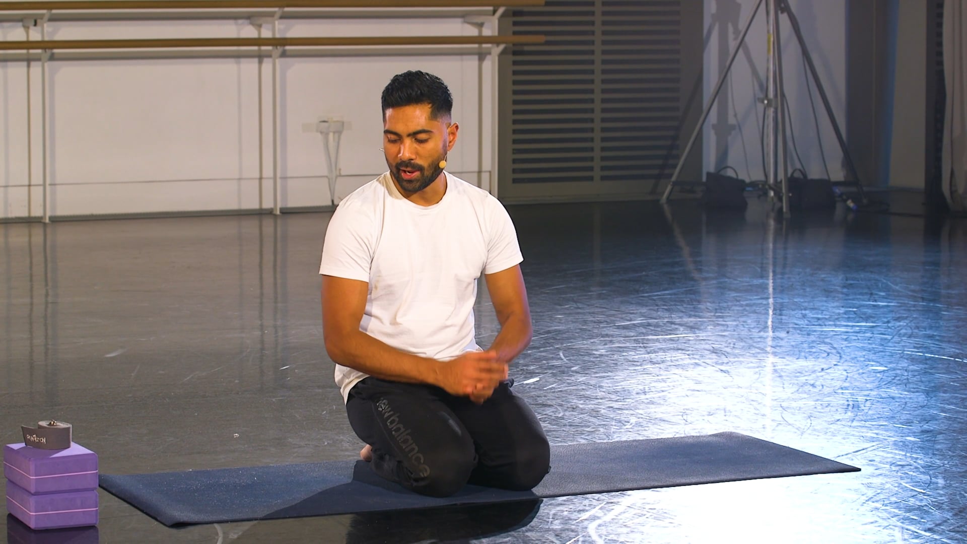 a man sitting on a yoga mat in a room.