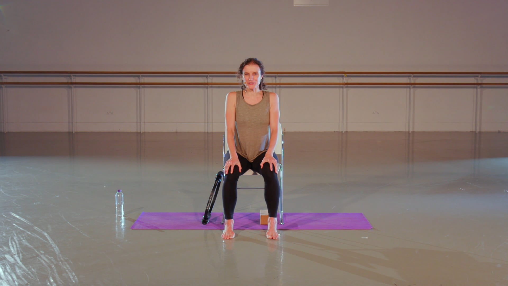 a woman sitting on a yoga mat with her legs crossed.