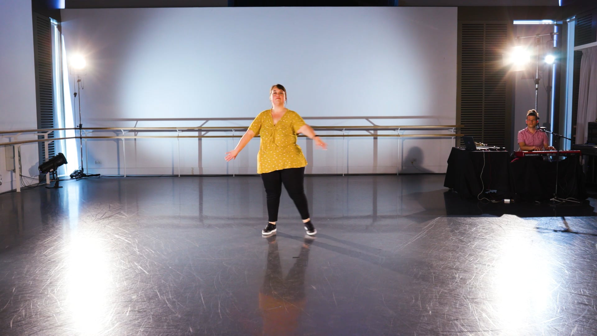 a woman in a yellow shirt is dancing on a stage.