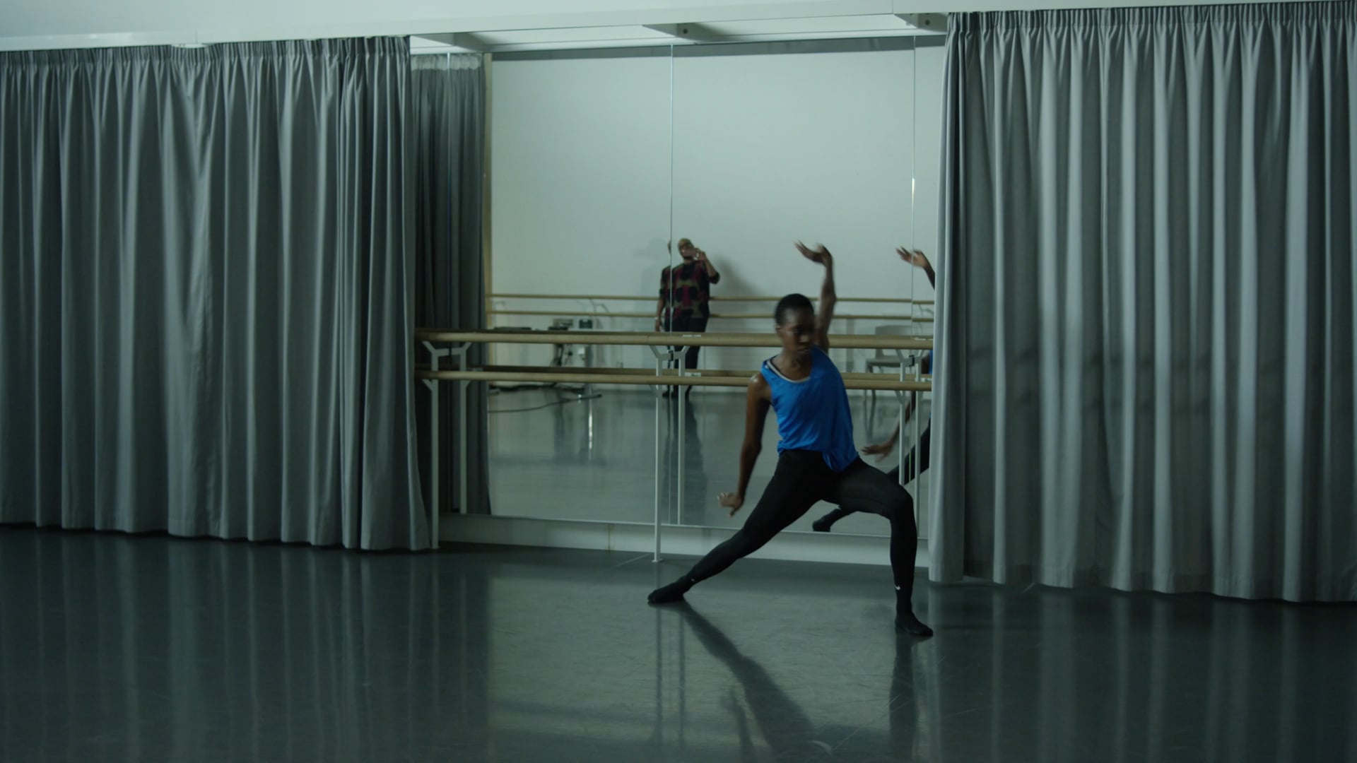 a woman standing in front of a mirror in a dance studio.