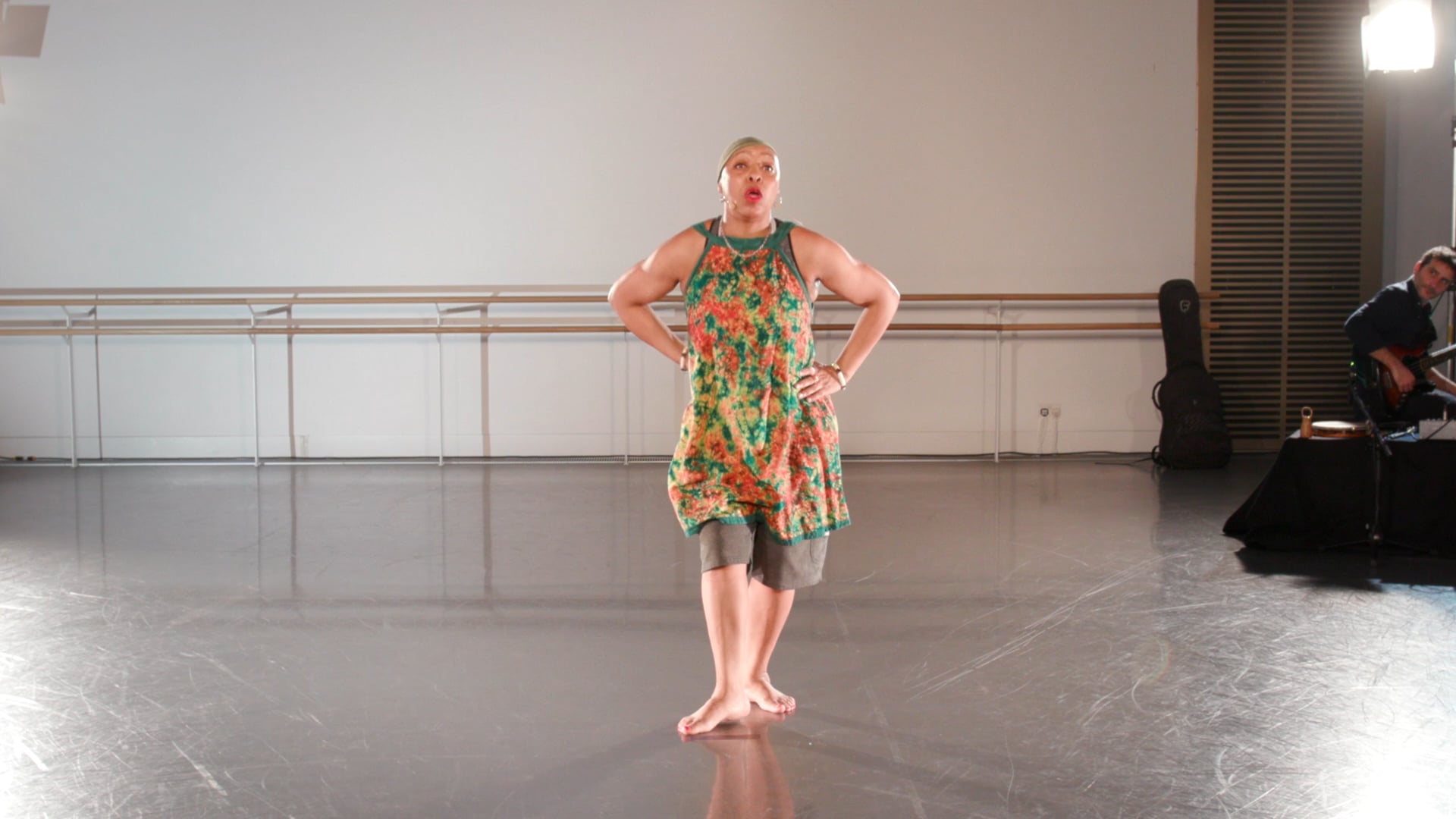 a man standing in a dance studio with his hands on his hips.