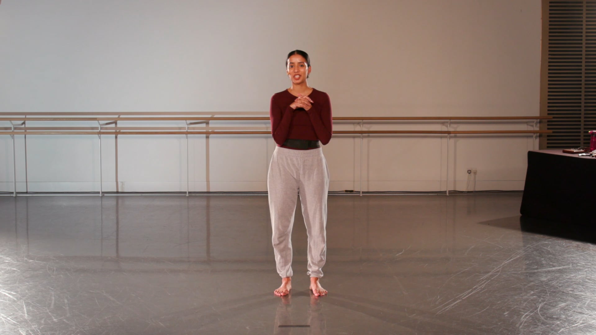 a woman standing in a dance studio with her arms crossed.