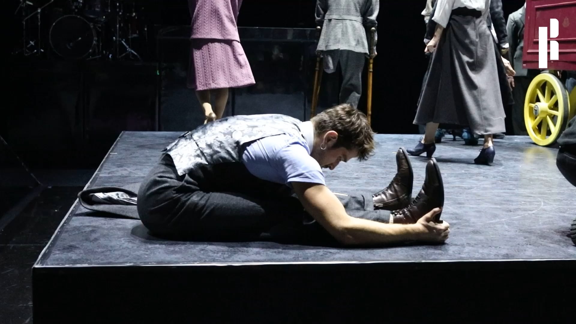 a man sitting on top of a stage holding a shoe.