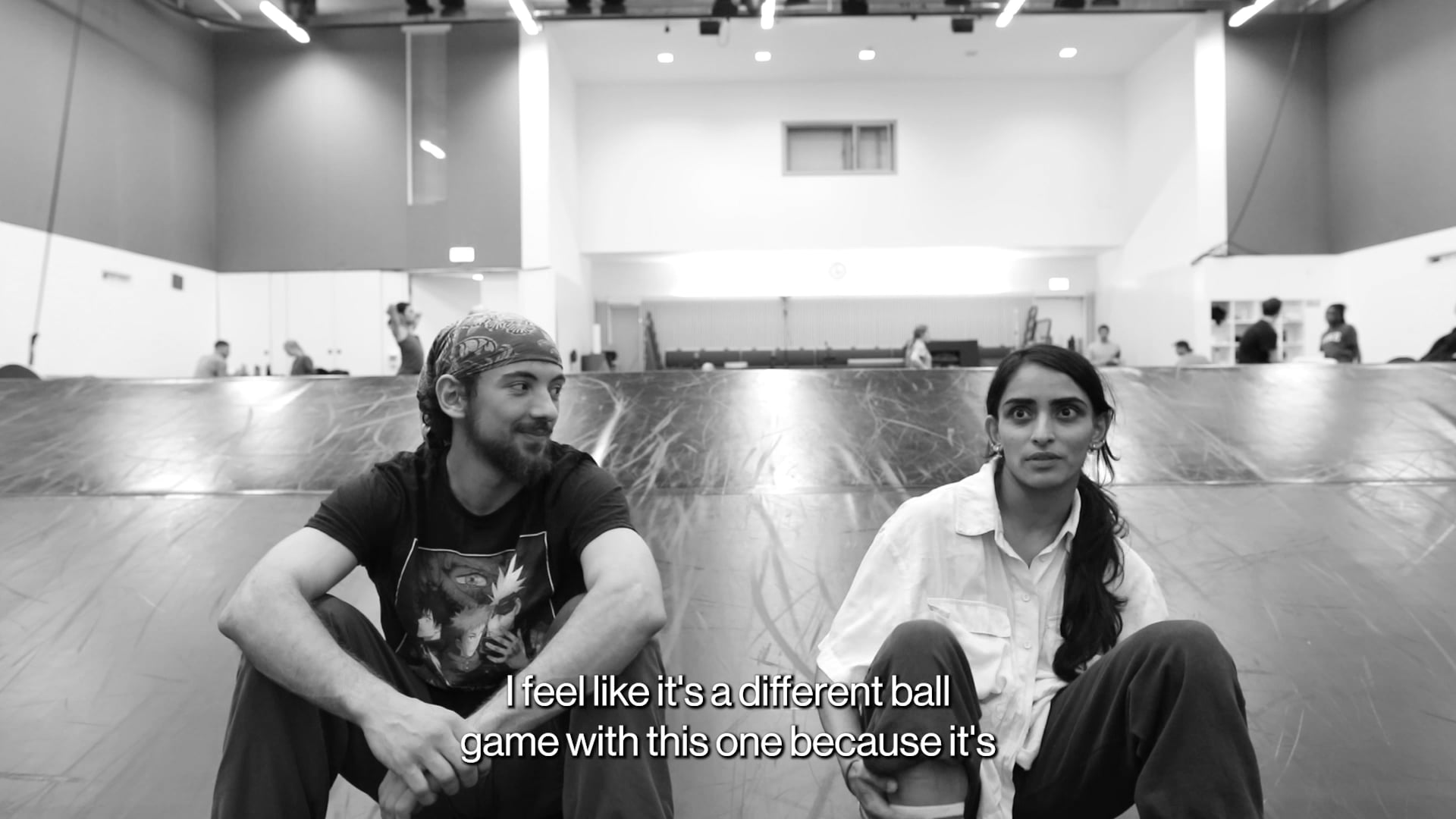 a man and a woman sitting on the floor in a gym.