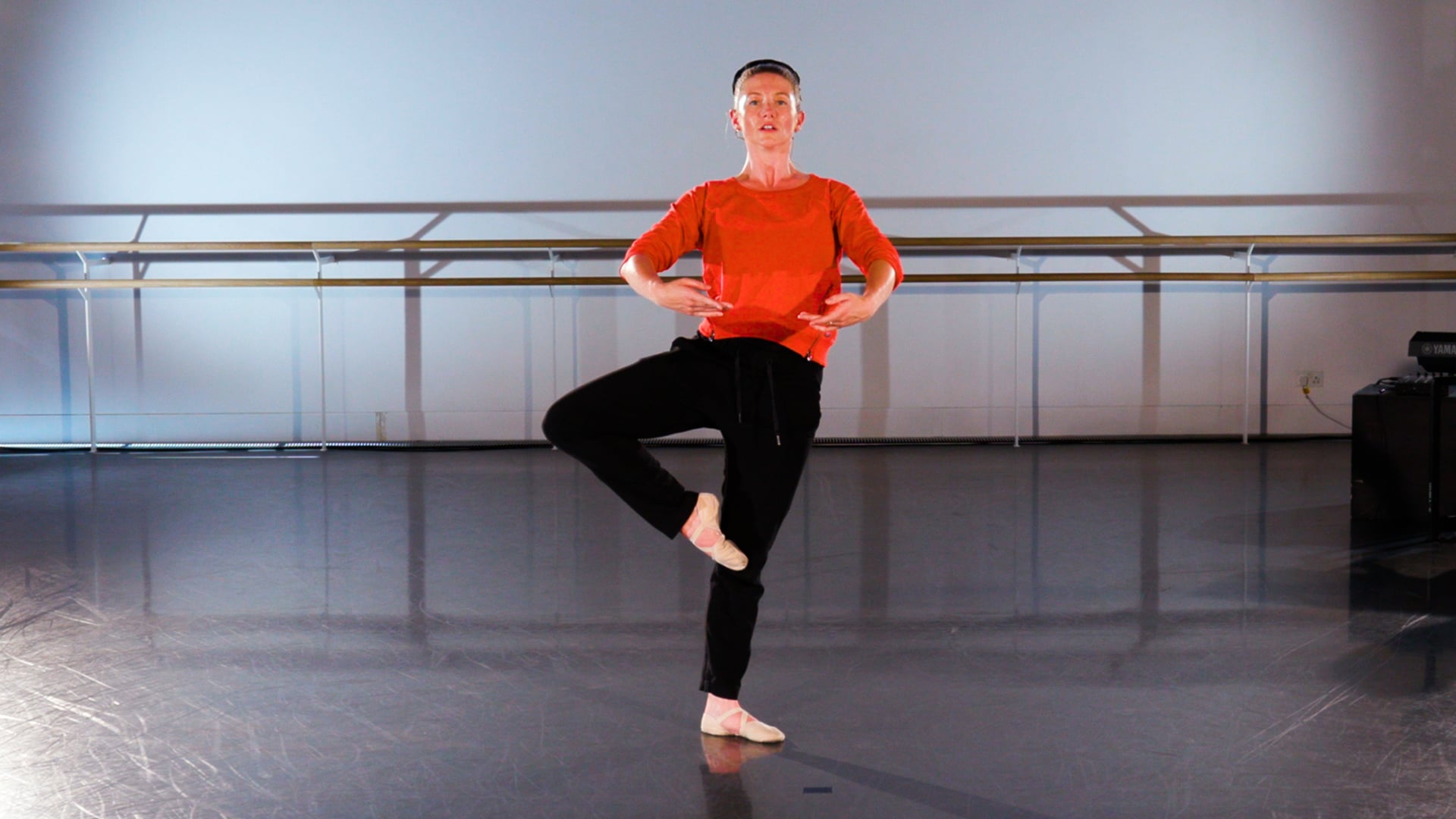 a man standing on one leg in a dance studio.