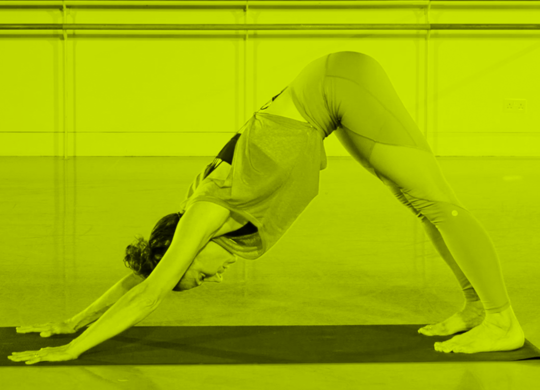 Female teacher doing a perfect downward facing dog's yoga pose.