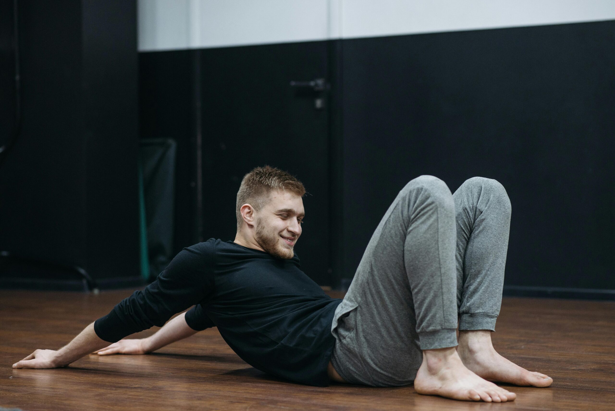 Pilates position where a man in a black t-shirt is ready to roll like a ball