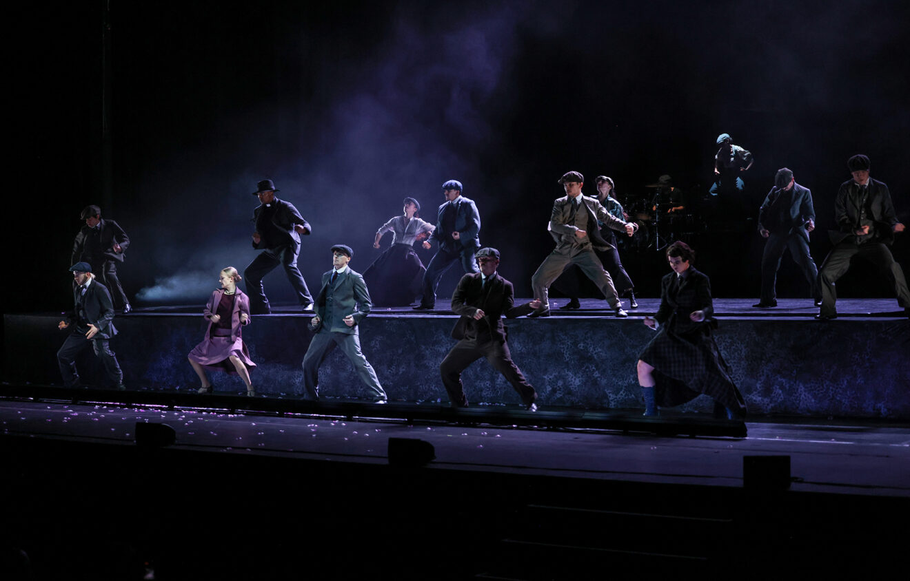 Rambert's Peaky Blinders in performance. dark image with daners daning on stage dressed in Peaky Blinders cast