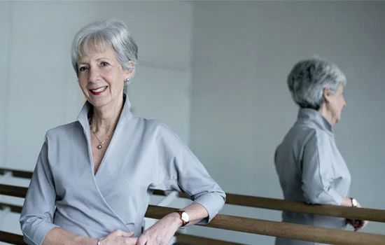Dame Sue Street in front of a mirror with her arm restig on a ballet bar