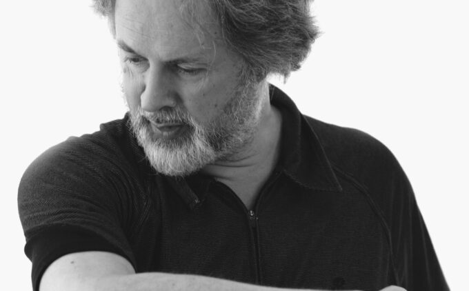 A black and white image of Richard Aslton looking to the bottom left of the screen wearing a black tshirt