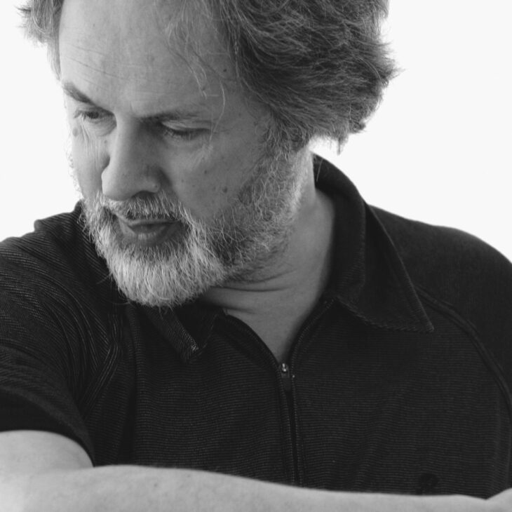 A black and white image of Richard Aslton looking to the bottom left of the screen wearing a black tshirt